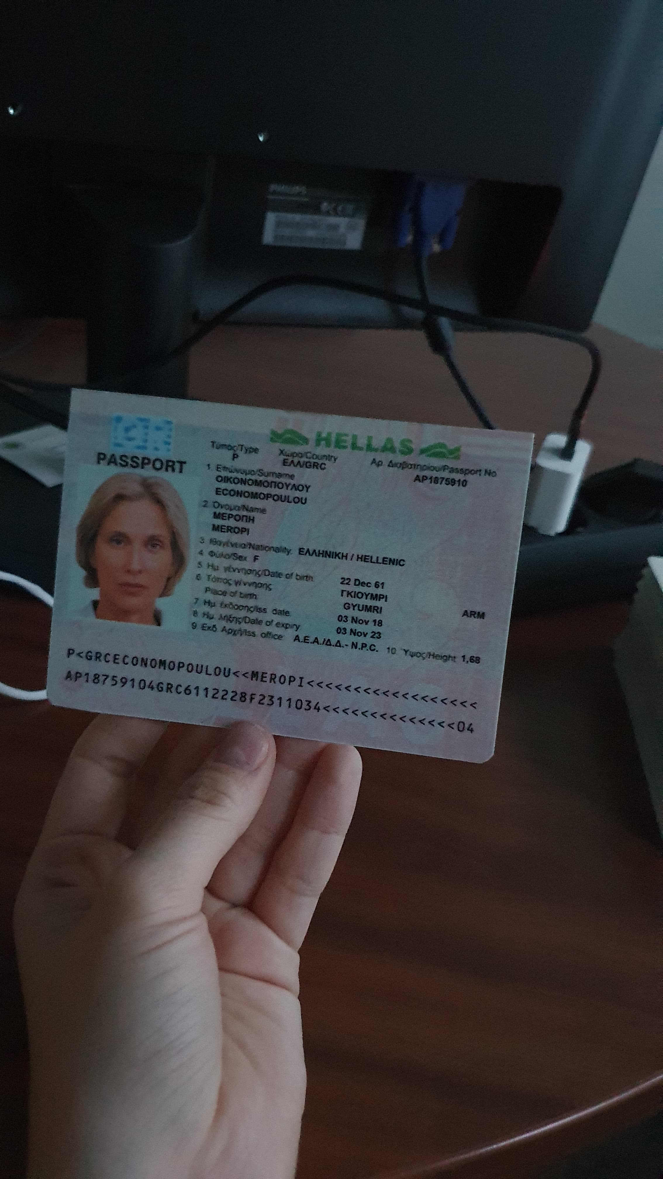 Passaporto greco tenuto in mano in una stanza quasi buia, documento fittizio del dataset MIDV-2020